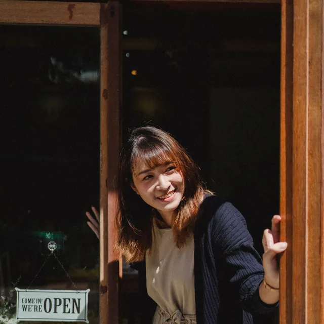 A shop owner welcoming customers in